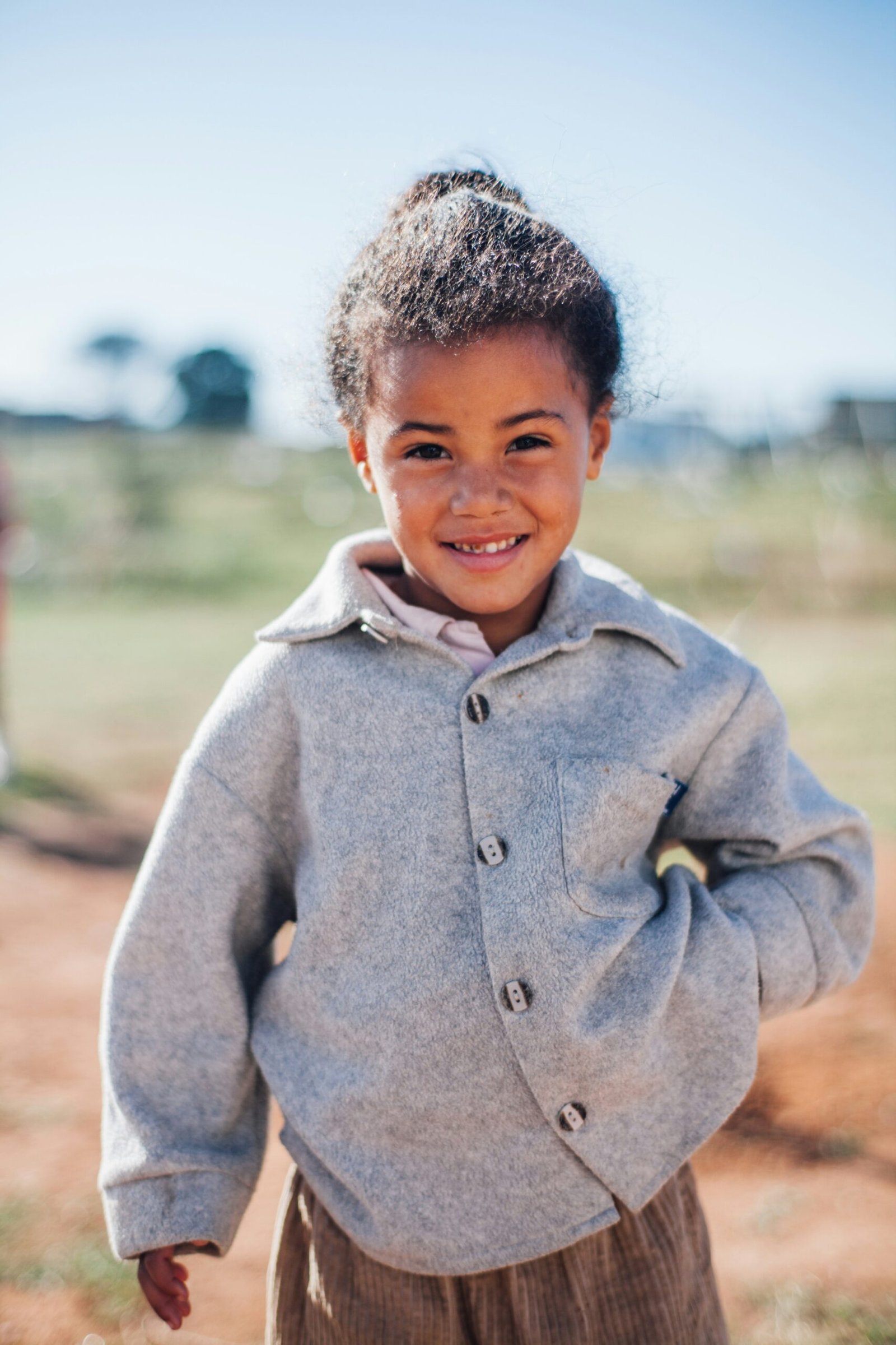 girl wearing grey button-up jacket while smiling